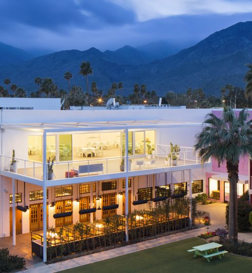 Overhead view of Saguaro Hotel at dusk, with outdoor seating areas and hills in the background