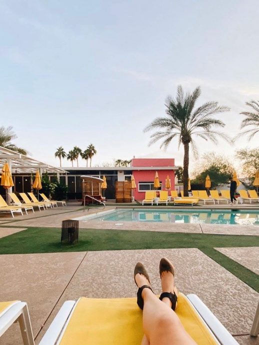 Person relaxing on a yellow lounge chair by the pool at a hotel in Palm Springs.
