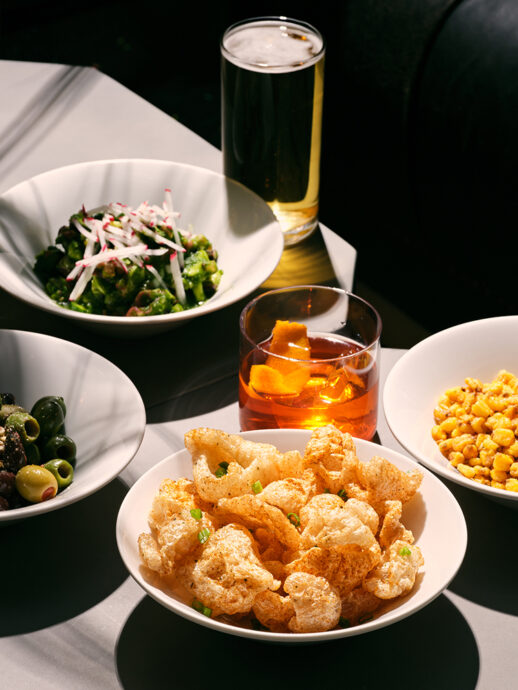 Table with assorted dishes and drinks, including popcorn, fried shrimp, salad, and cocktails.