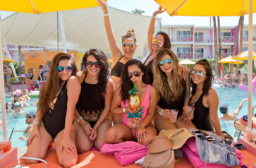 A group of people posing on a daybed by the pool