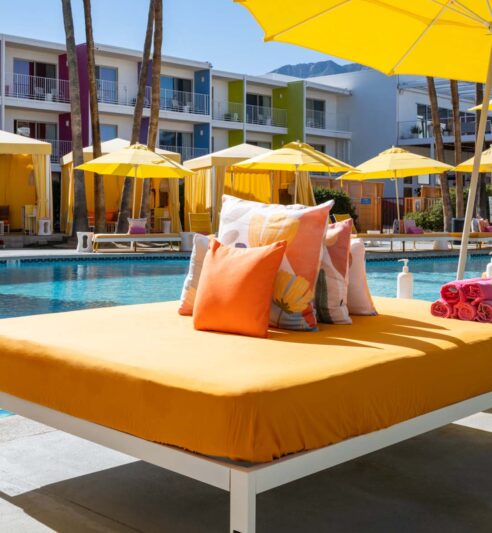 A pile of pillows on a daybed by the pool