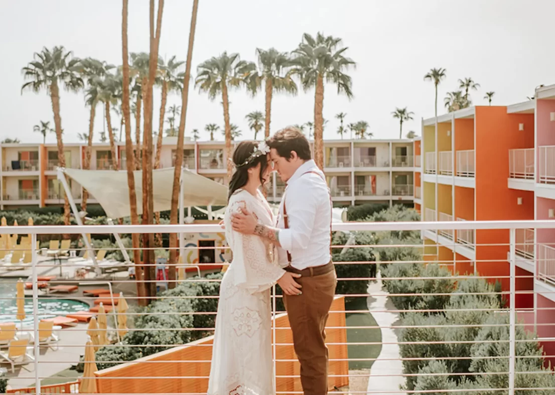 Bride and groom embrace on balcony at Palm Springs hotel wedding.