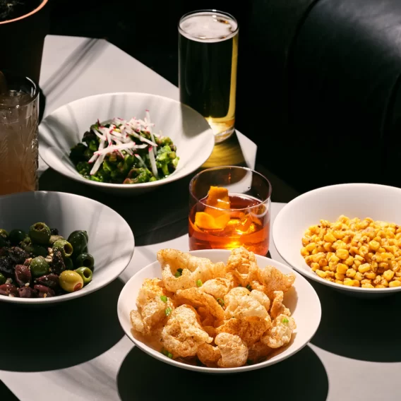 Table with assorted dishes and drinks, including popcorn, fried shrimp, salad, and cocktails.