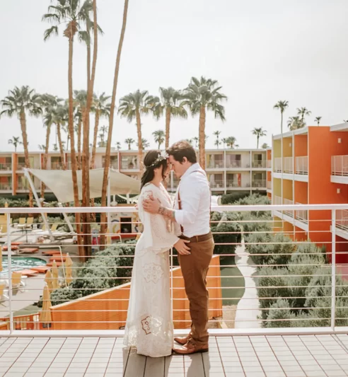 Bride and groom embrace on balcony at Palm Springs hotel wedding.